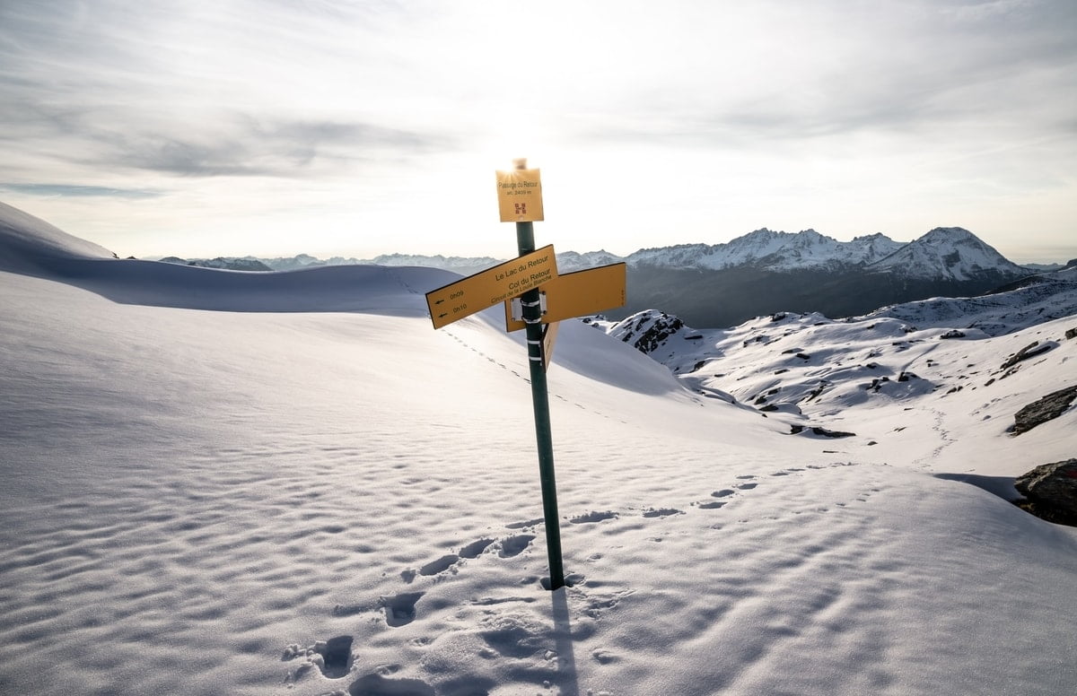 directional signs on a pole in the snow on a slope